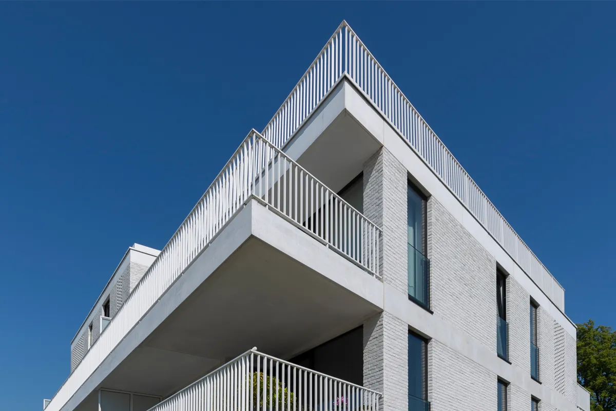 Appartementsgebouw met witte aluminium balustrades tegen een blauwe lucht